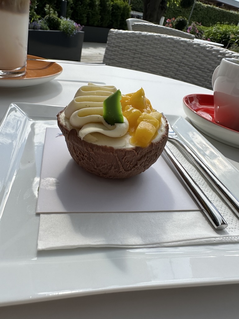 A cake shaped like half a coconut, filled with cream and fresh mango, on a café terrace