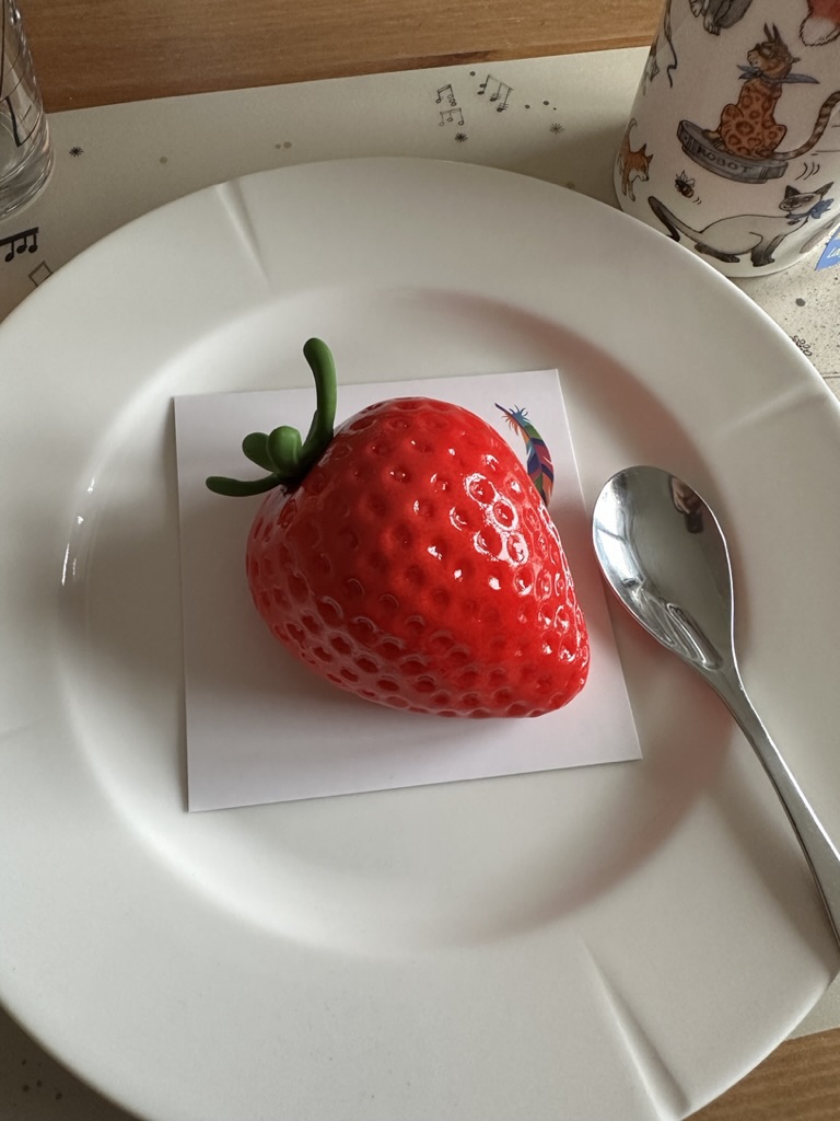 A cake shaped like a strawberry, on a plate at home