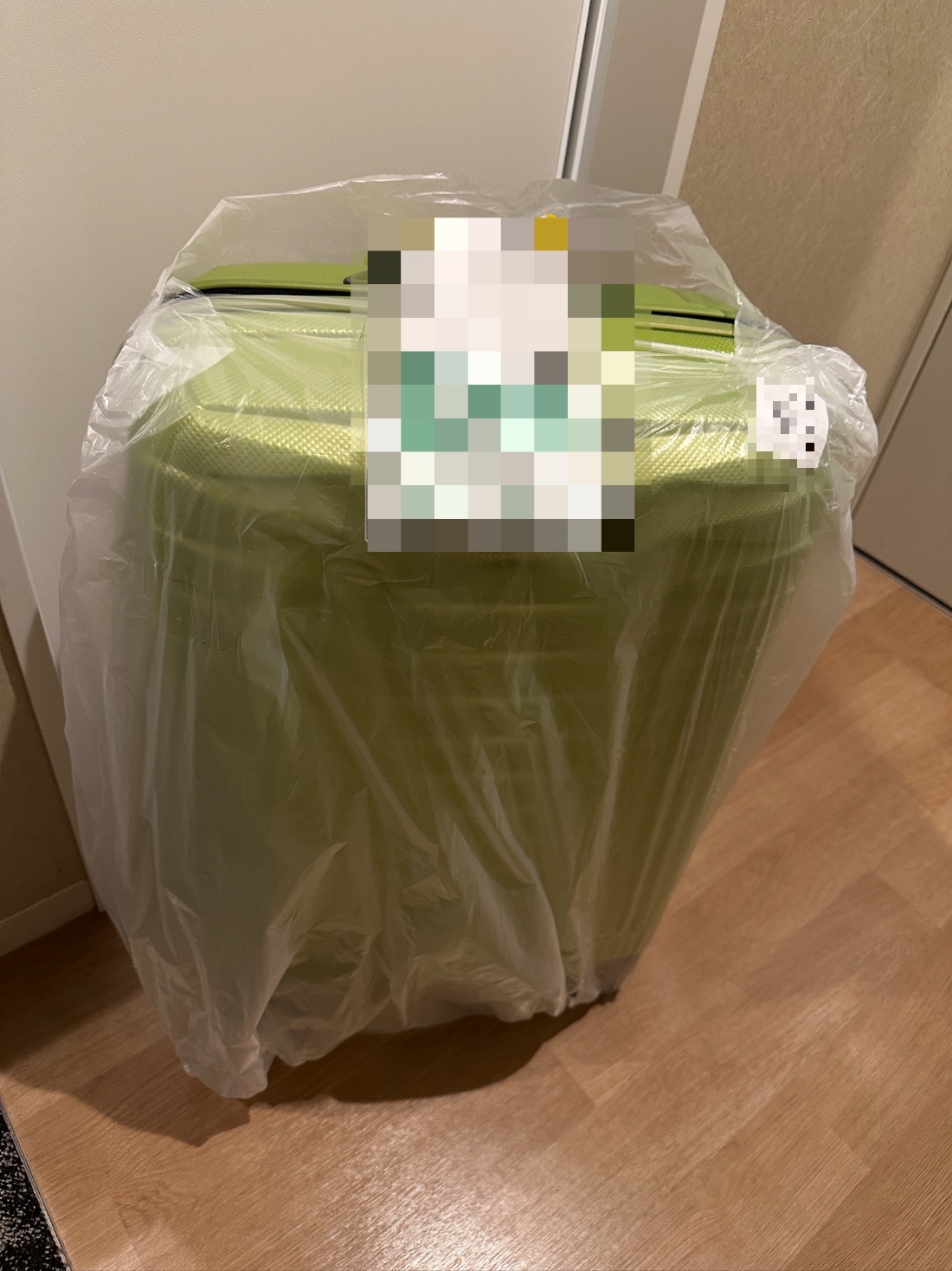 My suitcase waiting in the hotel room, wrapped in a protective plastic bag by the delivery company