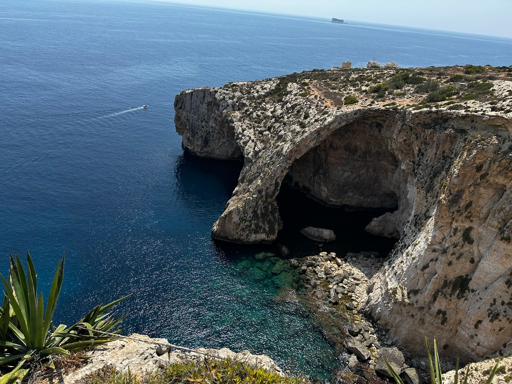 The sea cliff and arch at the Blue Grotto seen from the viewpoint, deep blue water below