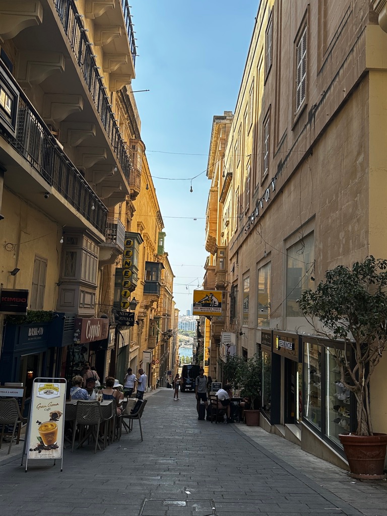 A narrow street in Valletta with cafe tables and balconies